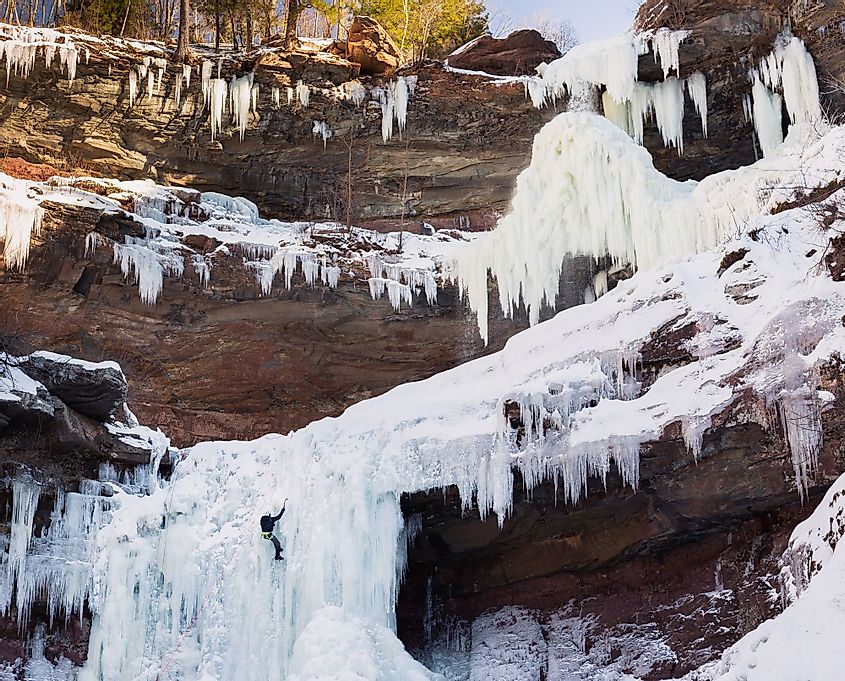 Adventurous hiker climbing the frozen Kaaterskill Falls during winter