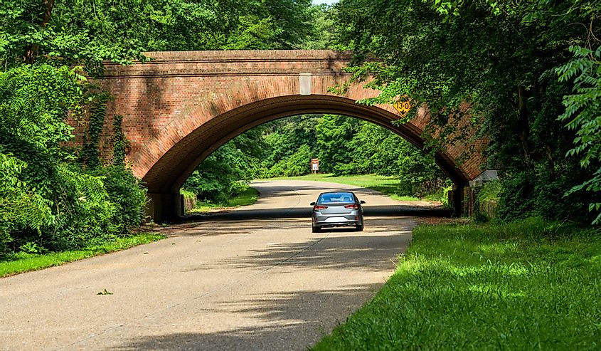 A sunny Spring morning view of winding and scenic Colonial Parkway at one of its many brick bridges in Colonial National Historical Park.