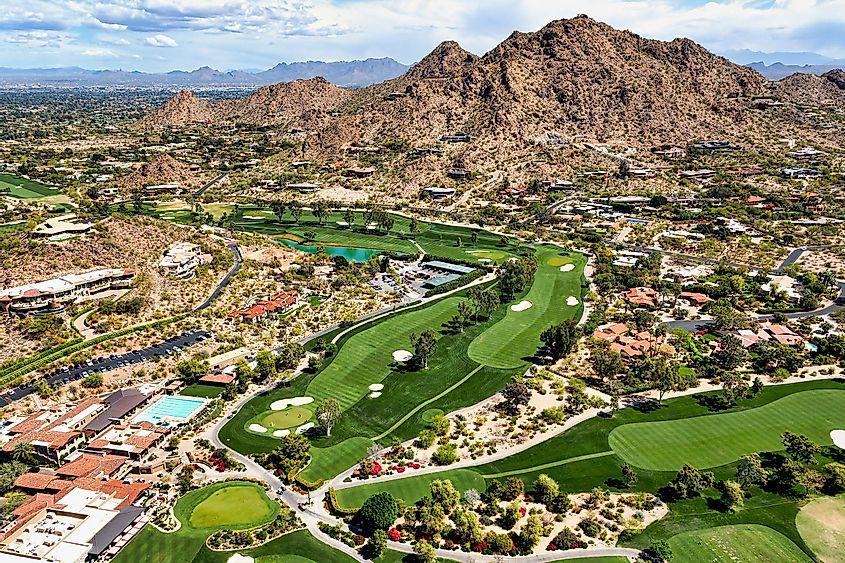 Aerial view of golf course in Paradise Valley, Arizona, with Mummy Mountain and McDowell Mountains in the distance.
