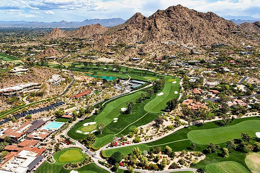 Aerial view of a golf course in Paradise Valley, Arizona, with Mummy Mountain and McDowell Mountains in the distance.
