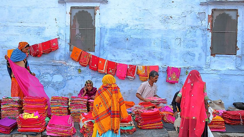 JODHPUR, RAJASTHAN, INDIA - DECEMBER 16, 2017: Colorful scenery at the market near Sardar Market with colorful fabric, women dressed with saris and blue walls in the background