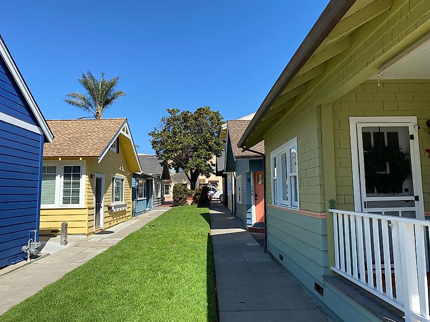 Soft-colored cottages line a long strip of lawn and dual sidewalks.