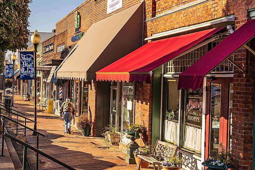 Pittsboro, North Carolina USA-02 20 2021: An Old Man Bent With Age Walks Toward a Barber Shop in Downtown Pittsboro.