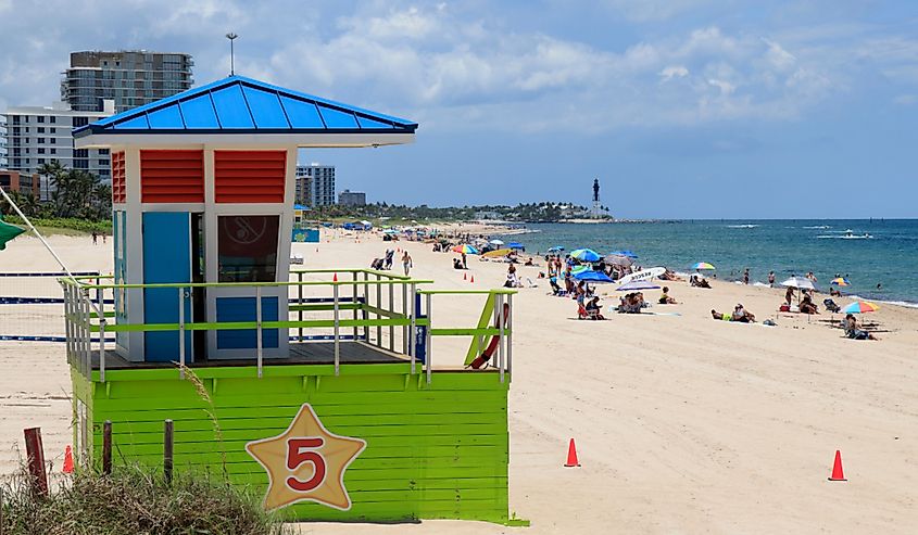Pompano Beach Atlantic Ocean coast looking north toward the Hillsboro Inlet Lighthouse. Plenty of people enjoying Pompano Beach shore and water north of the pier