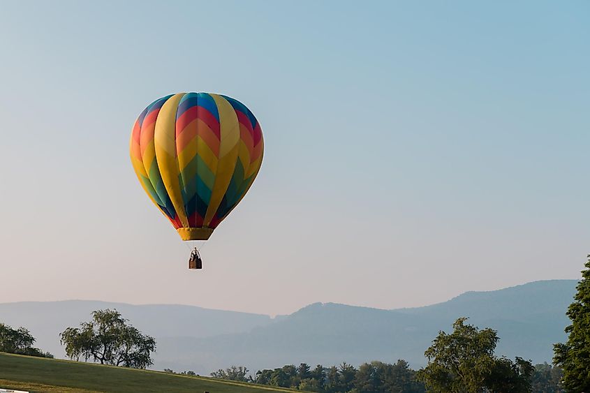 A brightly colored hot air balloon over a mountainous landscape in Wytheville Virginia during the Chautauqua Balloon Festival.