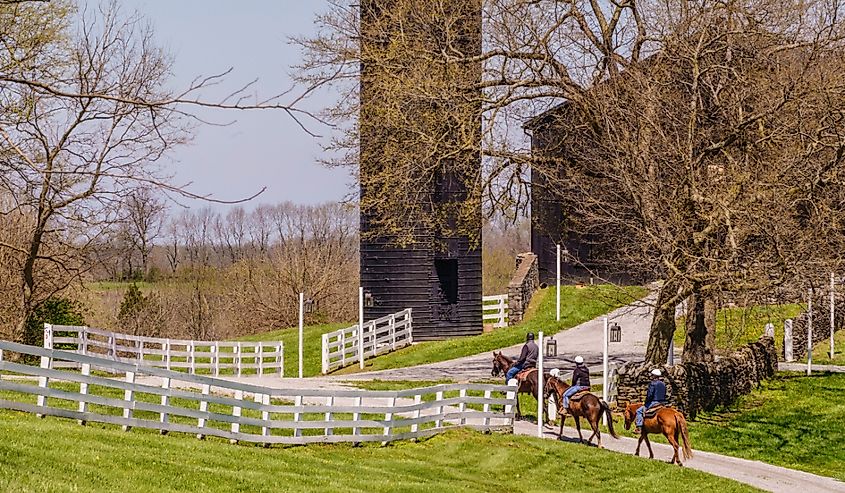 Three adult riders follow a trail toward an historic barn at the landmark destination of Shaker Village of Pleasant Hill on a sunny day in spring.