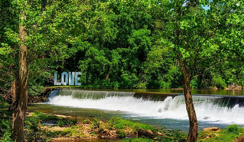 Love sign sits on the opposite New River Bank from Old Mill Resturant, at the end of a waterfall from a weir in Damascus, Virginia.