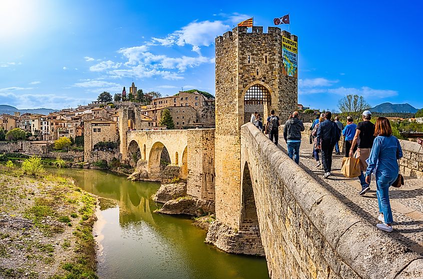 Tourists entering via the bridge over the river Fluvia in the medieval village de Besalú, Girona, Catalonia, Spain.