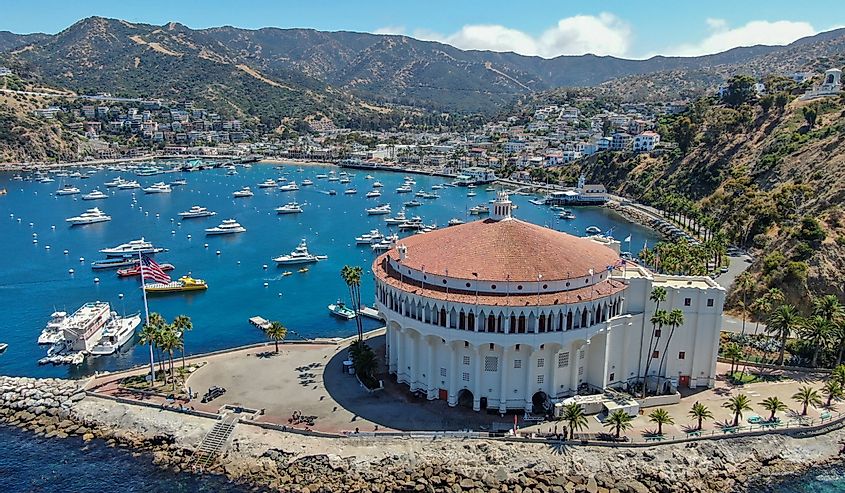 Вид с воздуха на казино Catalina и гавань Авалон с парусниками, рыбацкими лодками и яхтами, пришвартованными в бухте Калм-Бей, известной туристической достопримечательностью острова Санта-Каталина, Южная Калифорния.