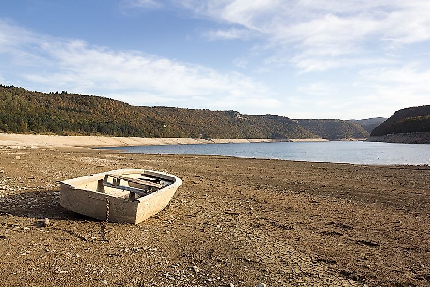 Abandoned boat resting on the cracked floor of a dry lake, highlighting severe water loss and drought conditions