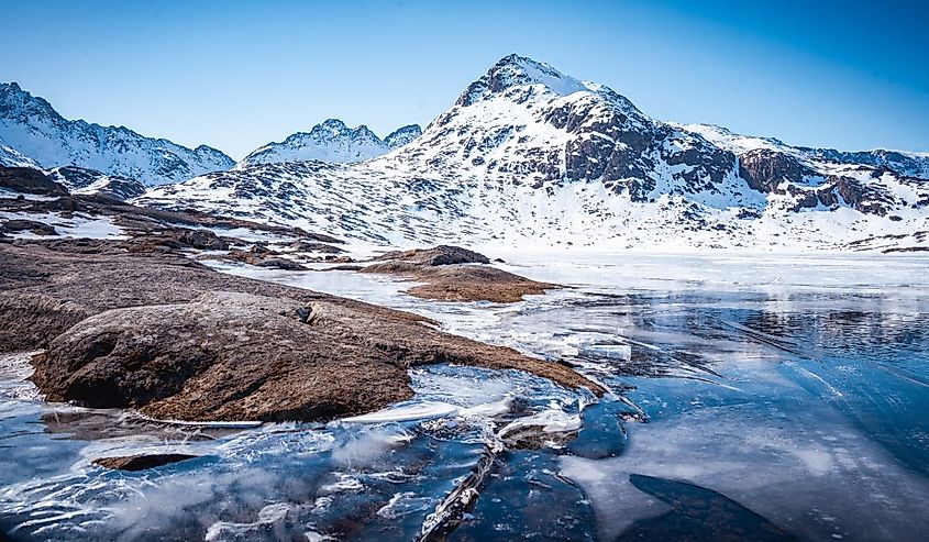 Snow-covered mountains and frozen lake in Greenland.