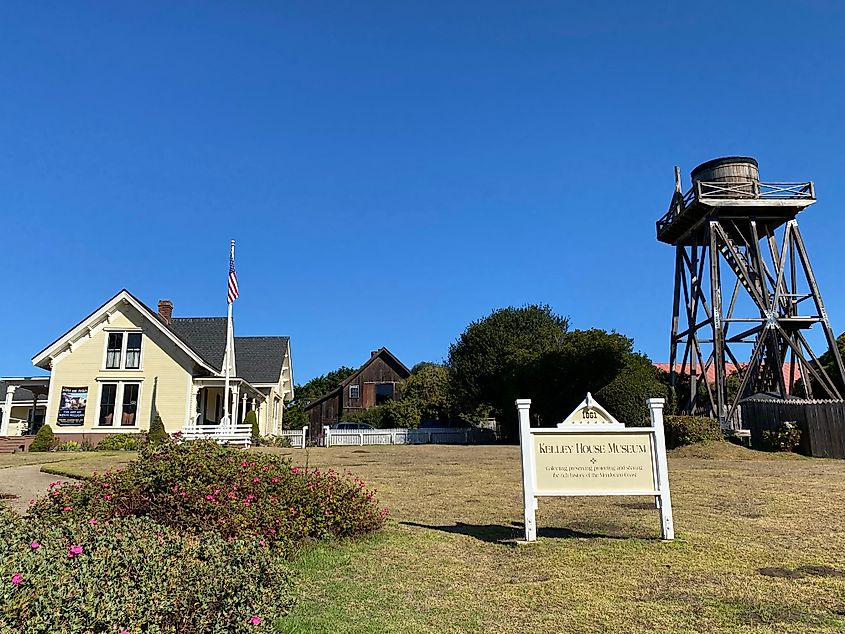 The cream-yellow house, wooden water tower, and spacious lawn of Mendocino's Kelley House Museum.