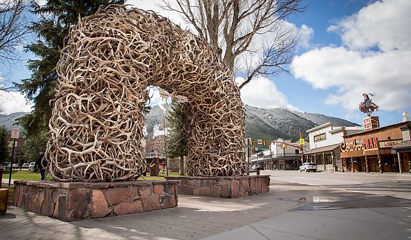 Famous Antler Arch at Jackson Town Square, Wyoming, with Cowboy Bar and ski slopes in the background