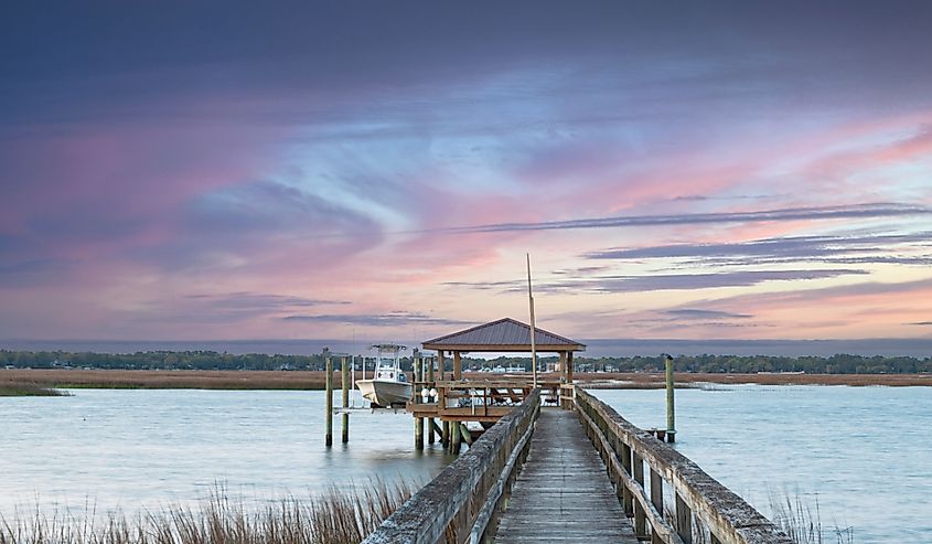 Dockside view of boathouse walking on dock with pink sky in Beaufort, South Carolina.