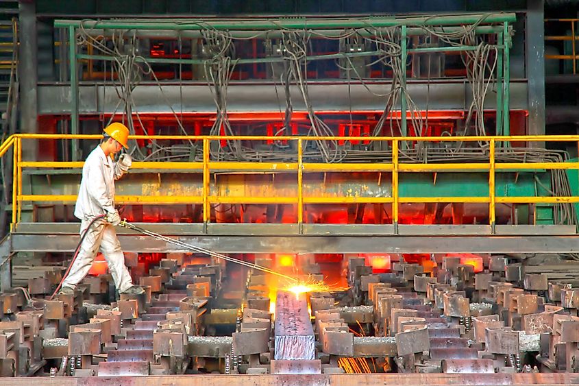 A worker cutting steel ingot behind the continuous casting machine in a steel plant in Tangshan City, Hebei Province, China.