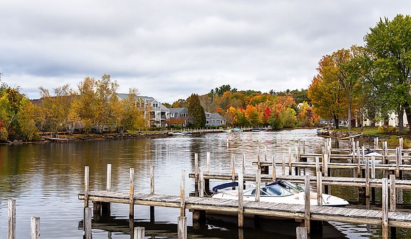 Wooden jetties on a river on a cloudy autumn day. Some waterside apartment buildings are visible among colorful autumnal trees on the other side of the river