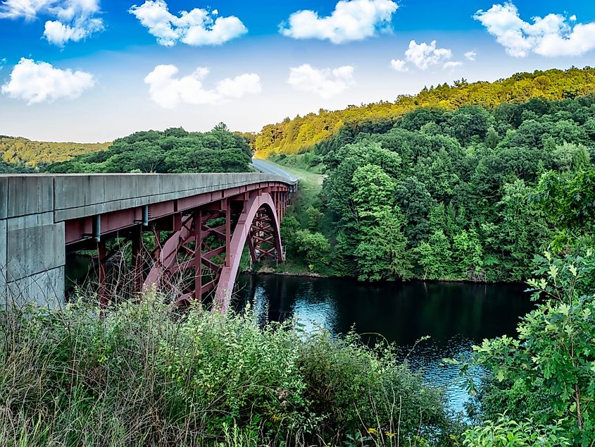 Bridge going over the Clarion River near Clarion, Pennsylvania, not far from the Allegheny National Forest. Green Trees, Bridge over the river and bright blue cloud filled sky in the background.