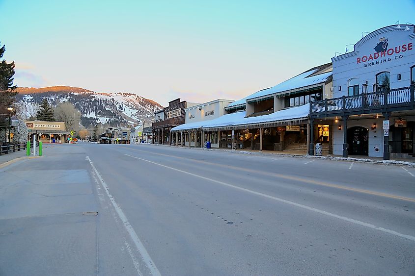 Downtown Jackson Hole Wyoming storefronts, signs, and lit antler arches in a snowy winter night 