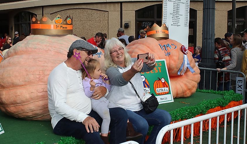Annual Pumpkin Festival yields thousands of visitors for food, rides, entertainment and all things Pumpkin. Family photo with largest pumpkin on display. Circleville, Ohio