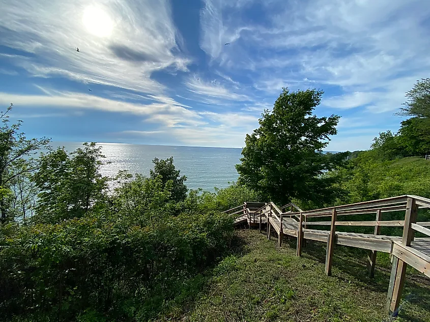 A wooden staircase leads down to the lake from a green bluff.