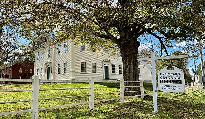 Side view of Prudence Crandall Museum with sign in front of fence in Canterbury, Connecticut