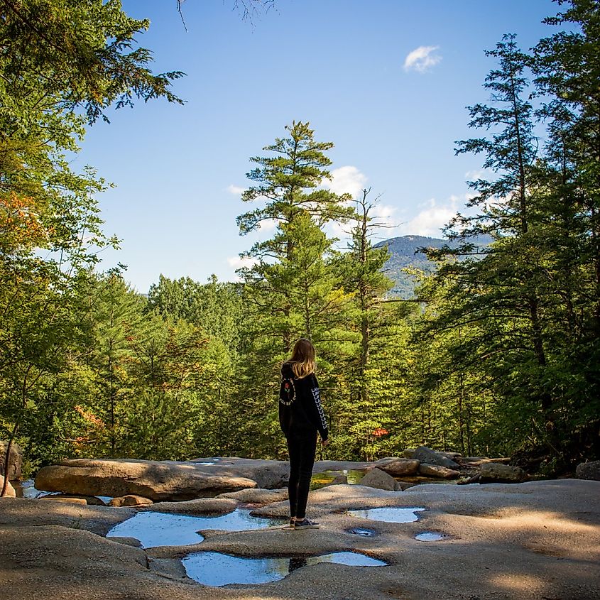 Conway, New Hampshire, a girl standing alone on the wet rocks of Diana's Baths along the Kancamagus Highway in New Hampshire on a chilly morning.