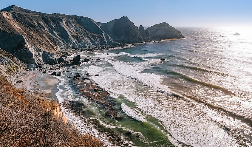 Steep cliffs drop to a narrow pocket beach on the Pacific coastline near Big Sur, California.