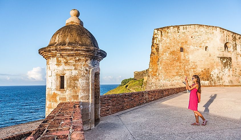 Old San Juan city tourist taking photo in Puerto Rico. Woman using phone taking pictures of ruins of watch tower of San Cristobal Castillo Fort