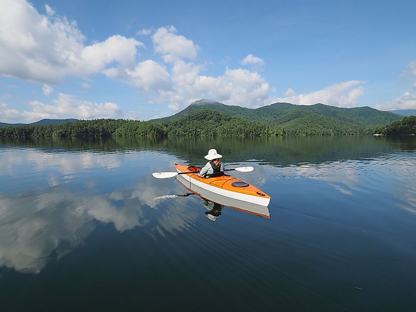 A woman kayaks on Lake Santeetlah, North Carolina, on a sunny summer day. 