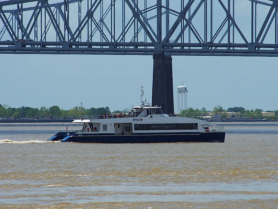 A ferry crosses the Mississippi River under a bridge in New Orleans, via Wirestock on iStock.com