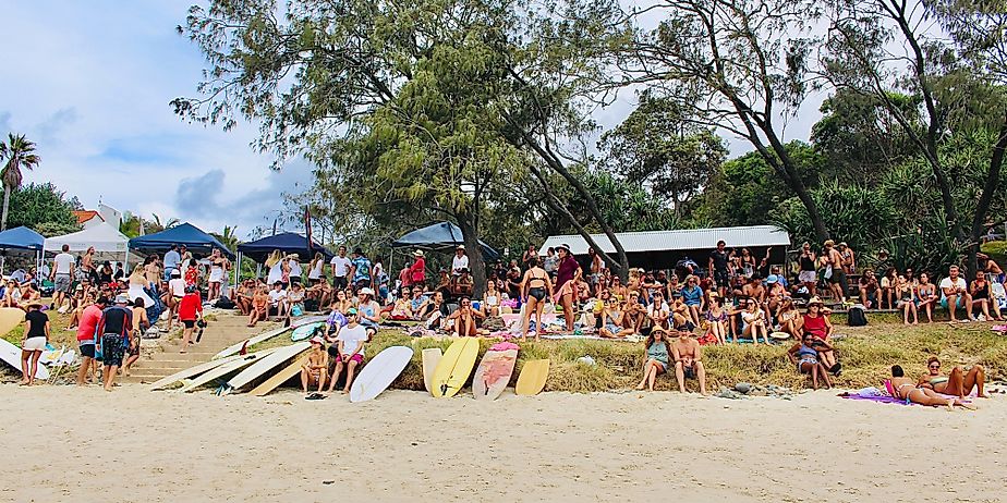 Horizontal landscape of crowd of people looking out to surfing festival competition at famous surf place Wategos beach Byron Bay Australia