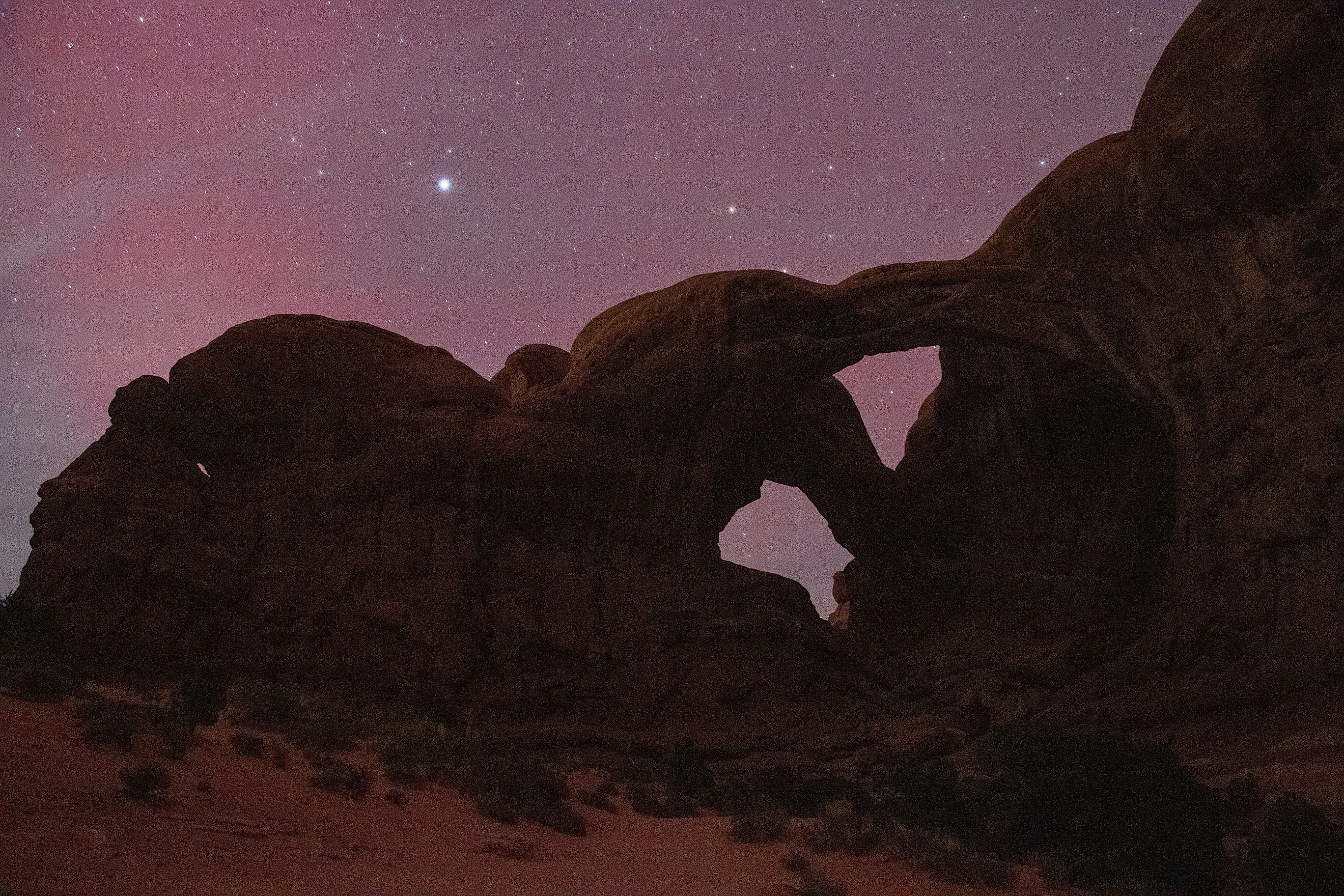 Rare aurora borealis dancing above Double Arch in Arches National Park, Utah - an extraordinary celestial event over iconic southwestern landscape