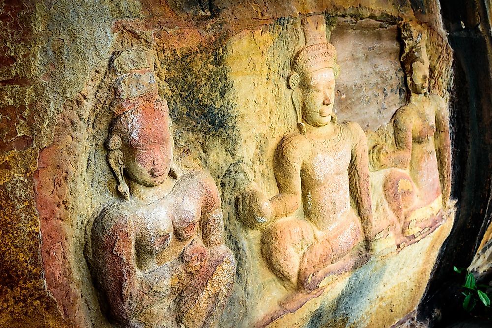 Faces on ancient stone of mountain in Cambodia, showing weathering and environmental damage due to acid rain.