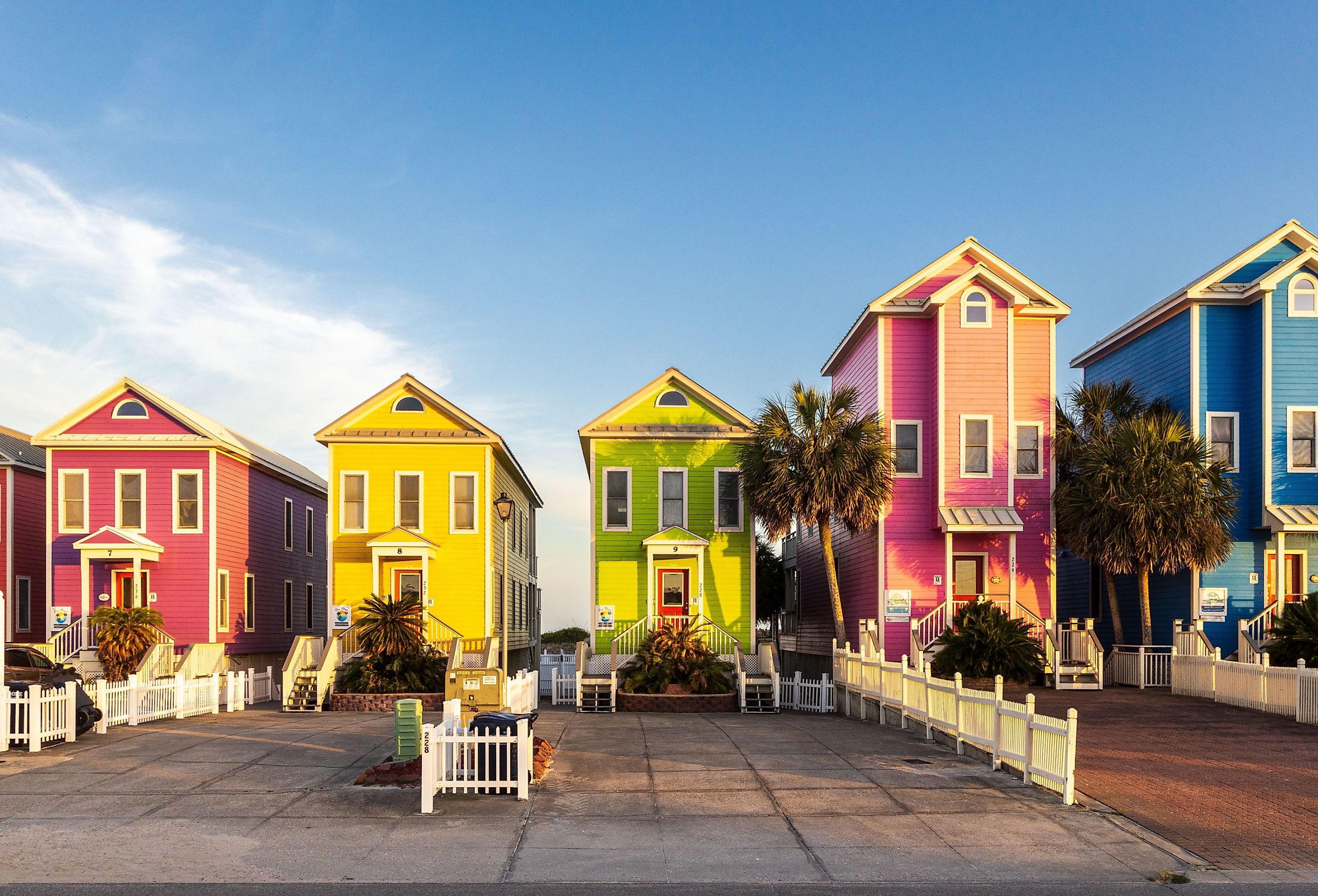 Photo of a row of colorful beachfront homes on a beautiful afternoon in St George Island, Florida. Image credit H.J. Herrera via Shutterstock.