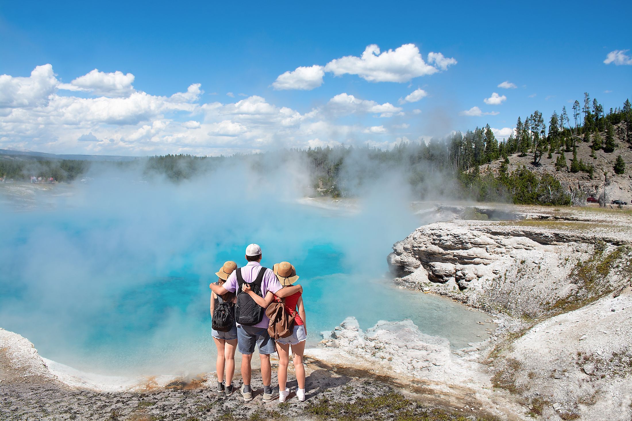 A family of tourists enjoying the view of a geyser in Yellowstone National Park. Wyoming, USA.