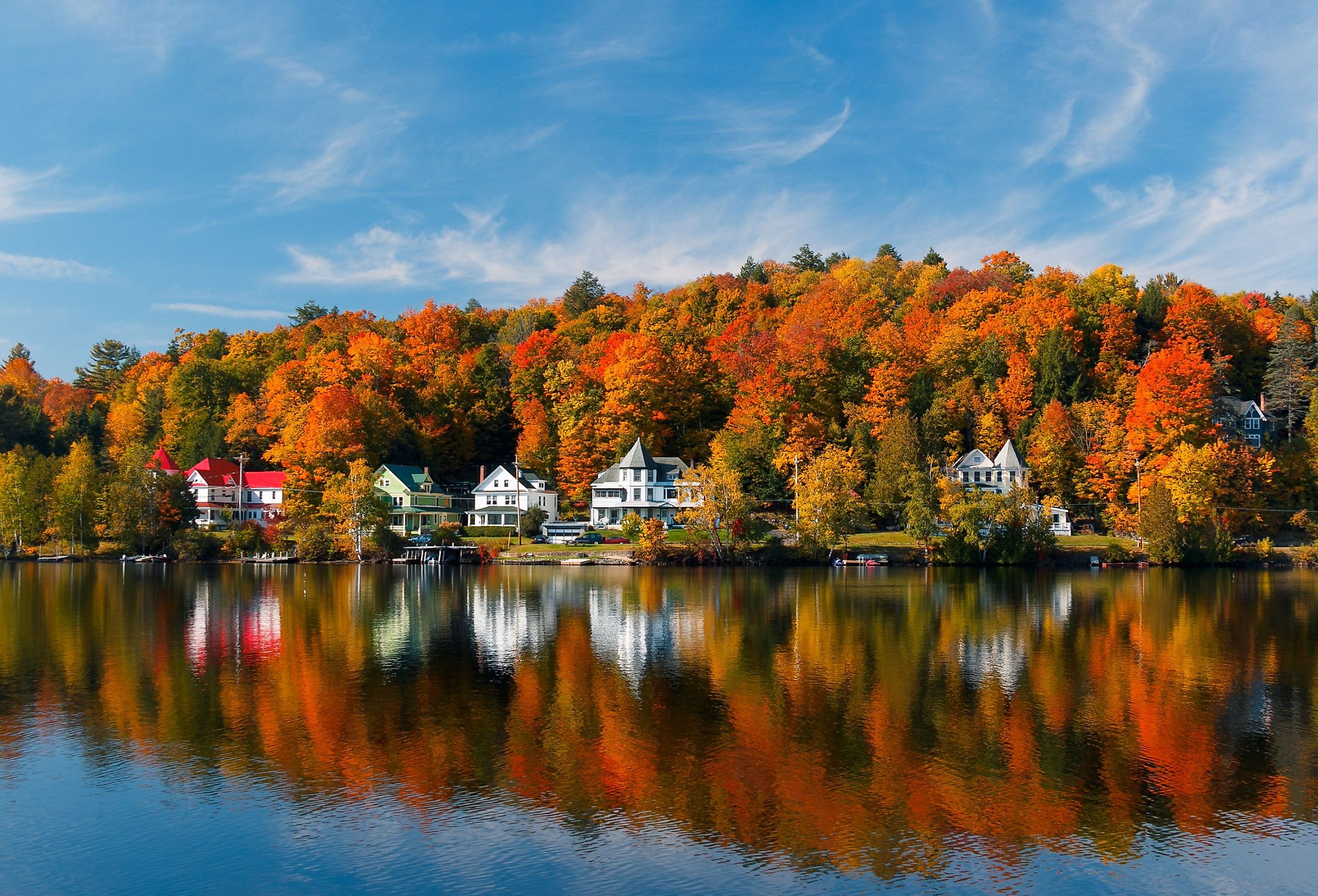 Homes in Saranac Lake, New York with fall foliage along the water.
