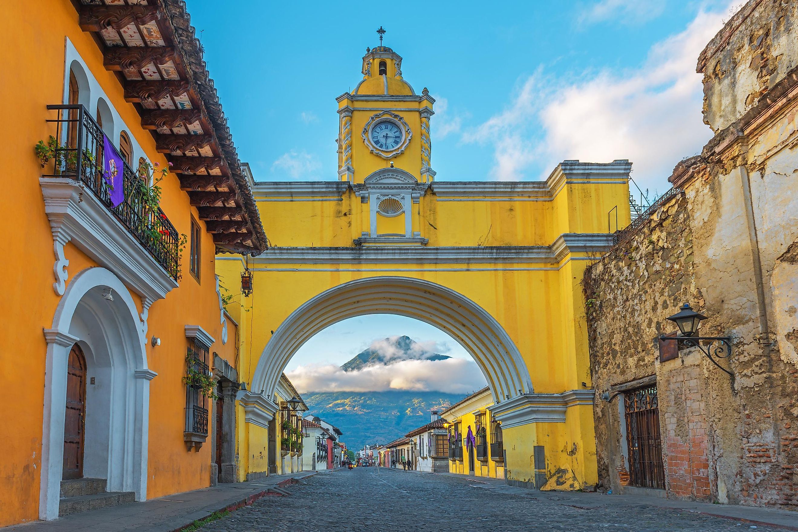A distance volcano can be seen through the golden arch of Antigua, Guatemala. Photo: SL-Photography