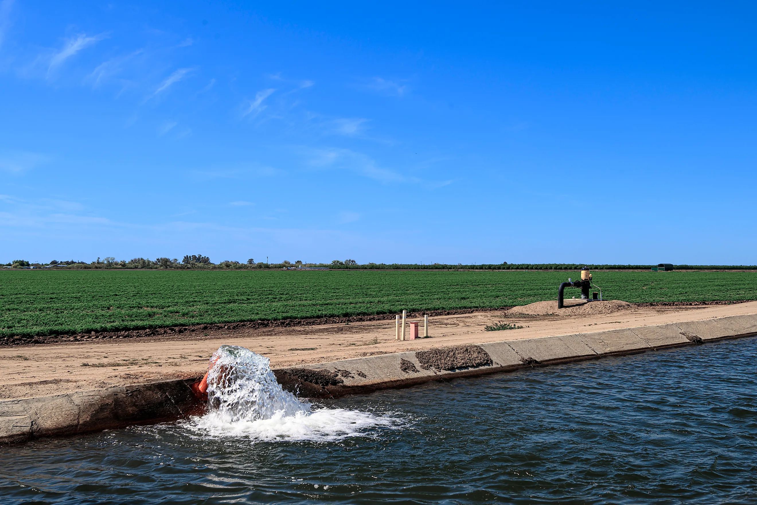 Groundwater is being pumped, from the San Joaquin Valley aquifer, into an irrigation canal, passing through California farmland.