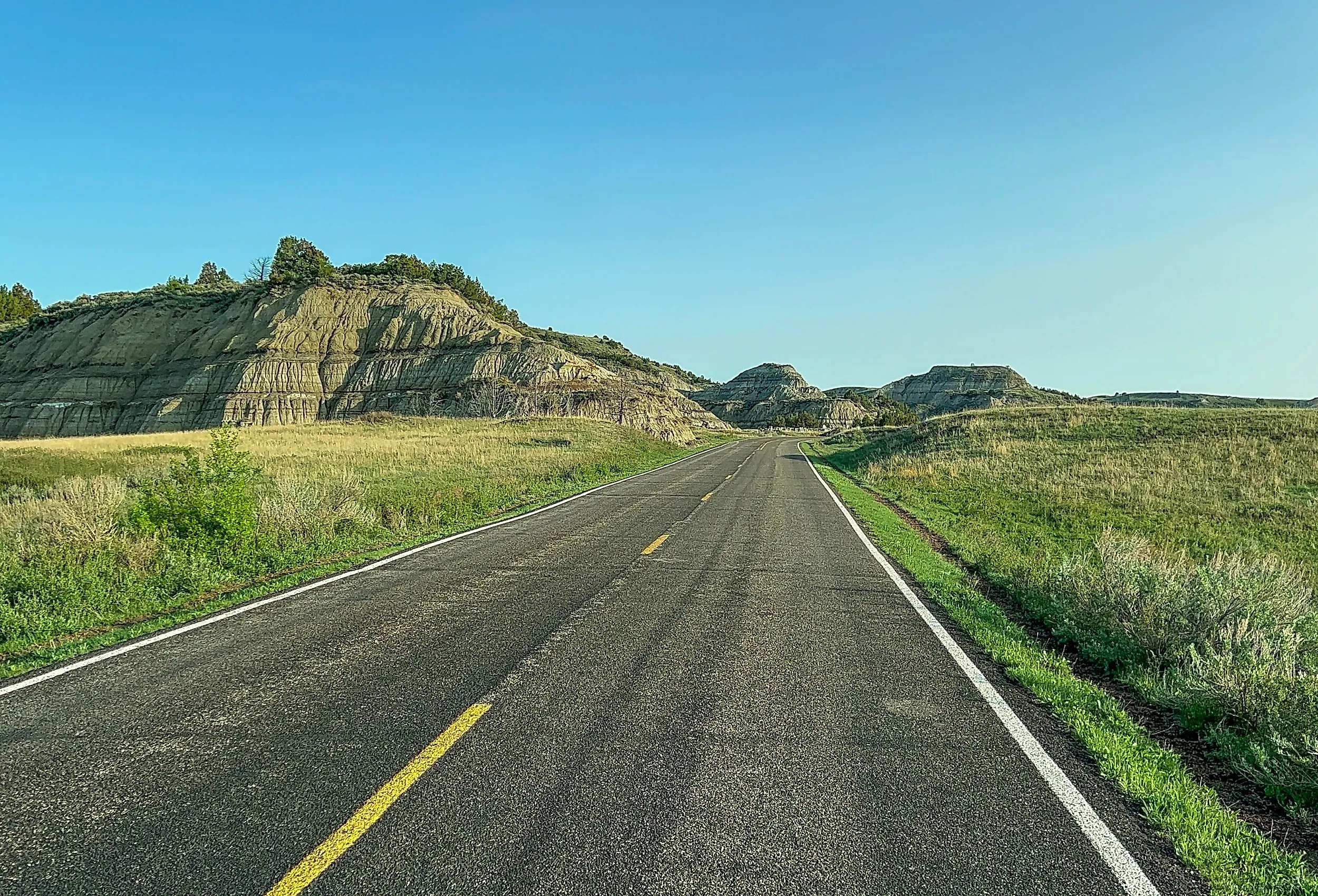 Driving through the badlands hills and mountains in Theodore Roosevelt National Park in North Dakota on a sunny day.