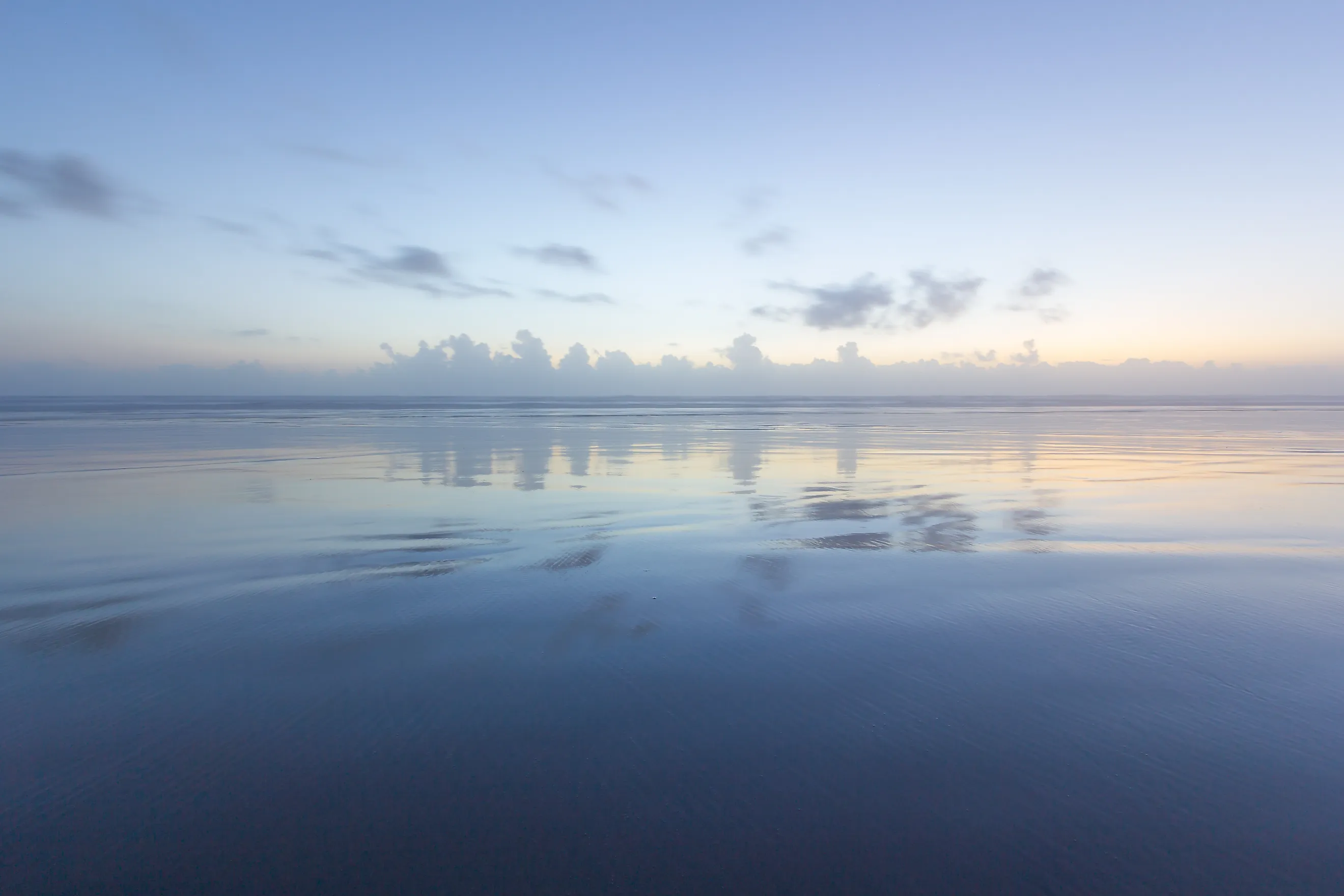 Ocean reflection of dusk sky on the beach. 