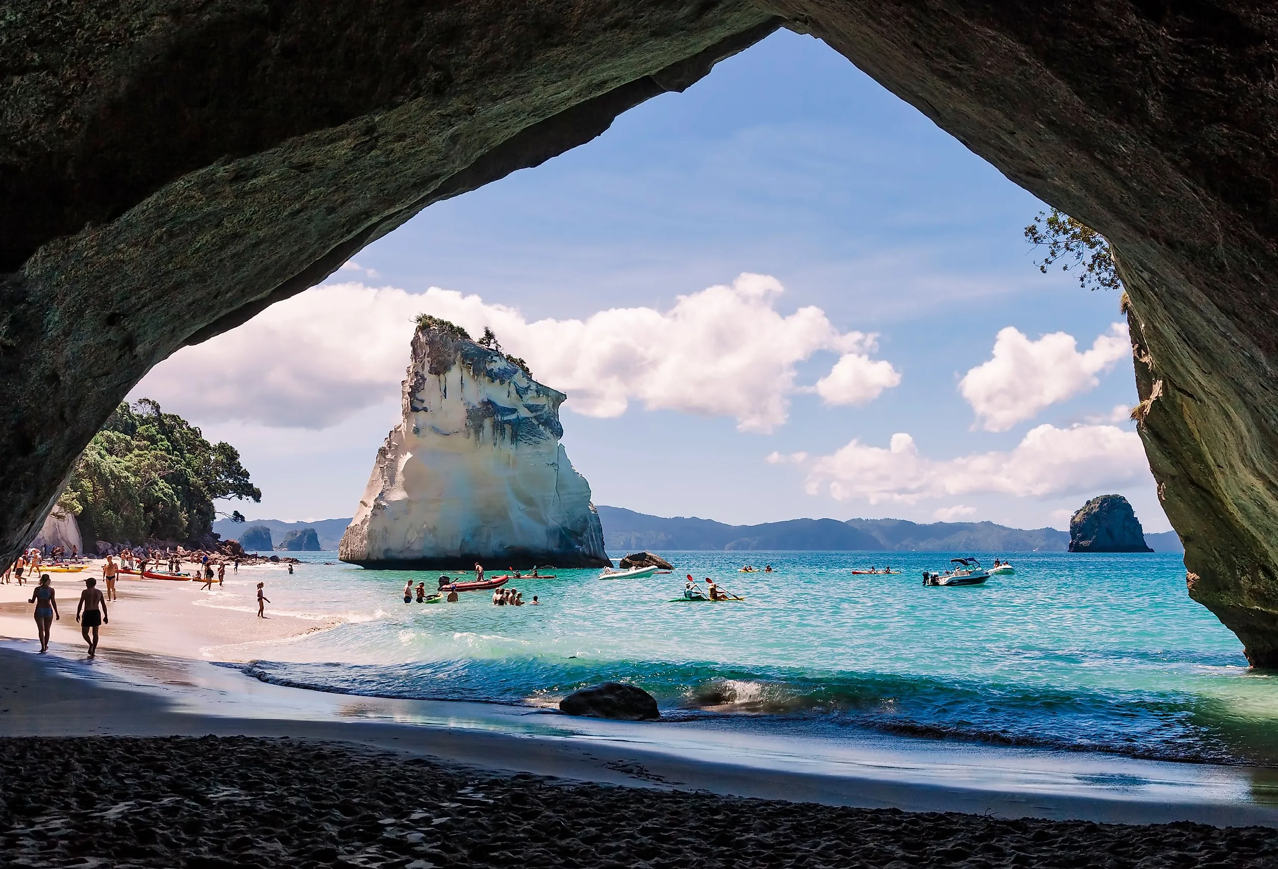 Cathedral Cove, beautiful beach with rocks and tourists in cave in Hahei, New Zealand. Image credit riekephotos via Shutterstock.com