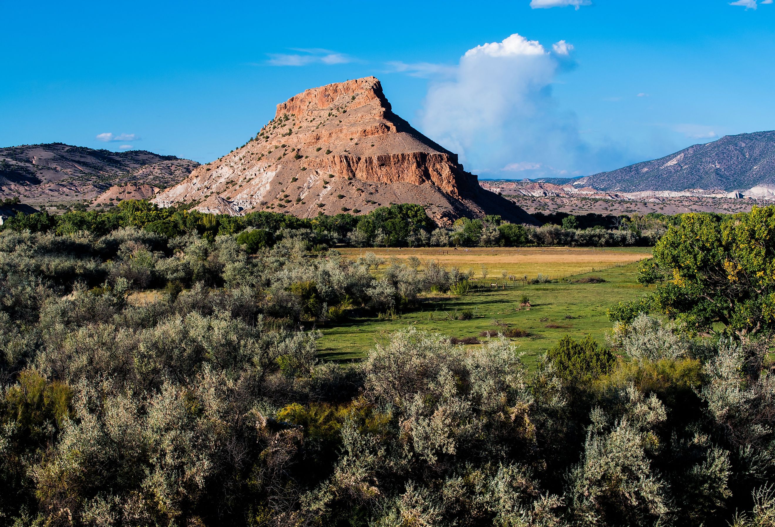 Colorful desert landsape of peaks and mountains above fields and farms in the lush Rio Chama valley near Abiquiu, New Mexico, USA. Image credit Jim Ekstrand via Shutterstock.