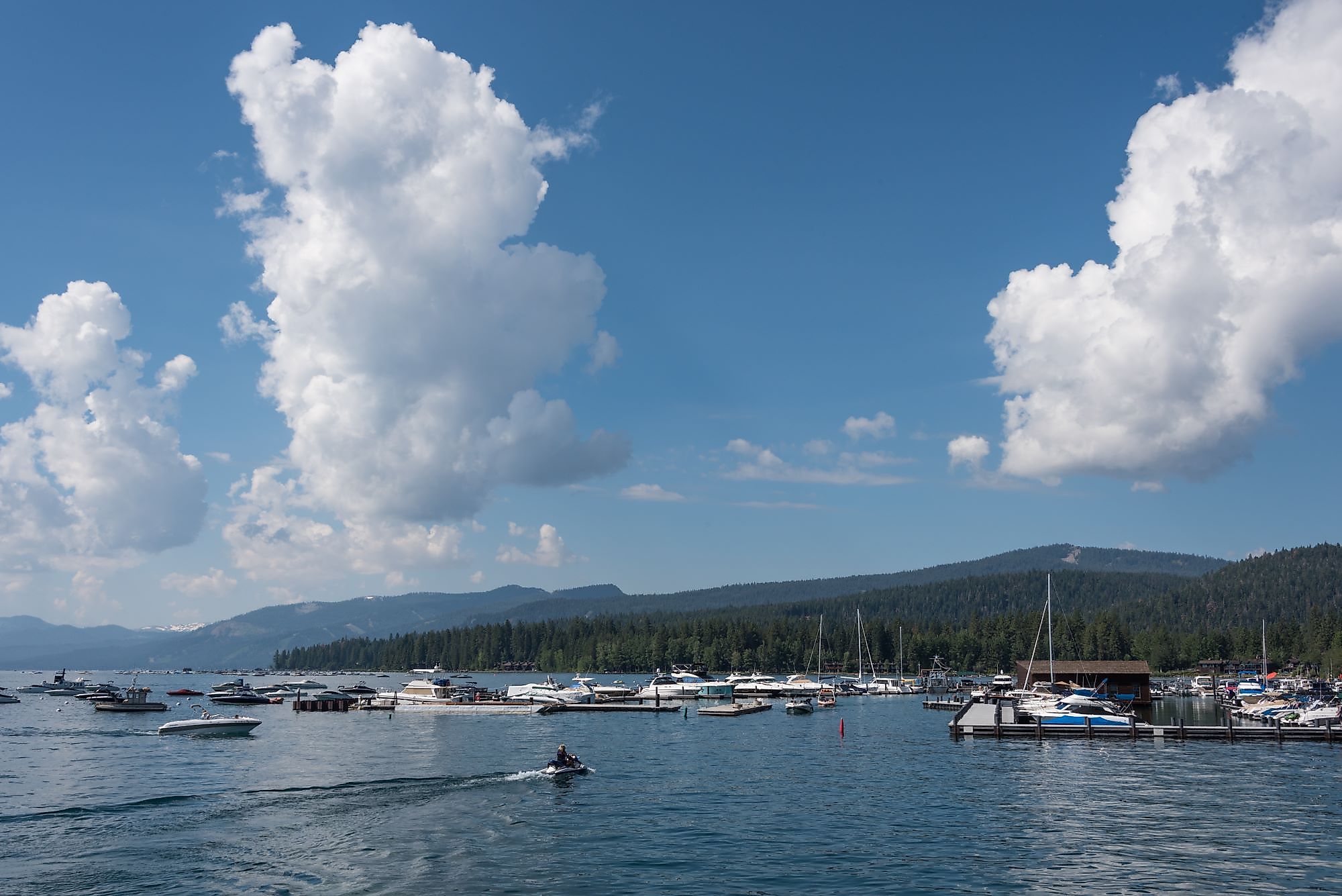 Beautiful clouds hang over the harbor area near Tahoe City, as boaters enjoy the warm summer weather and calm waters on Lake Tahoe.