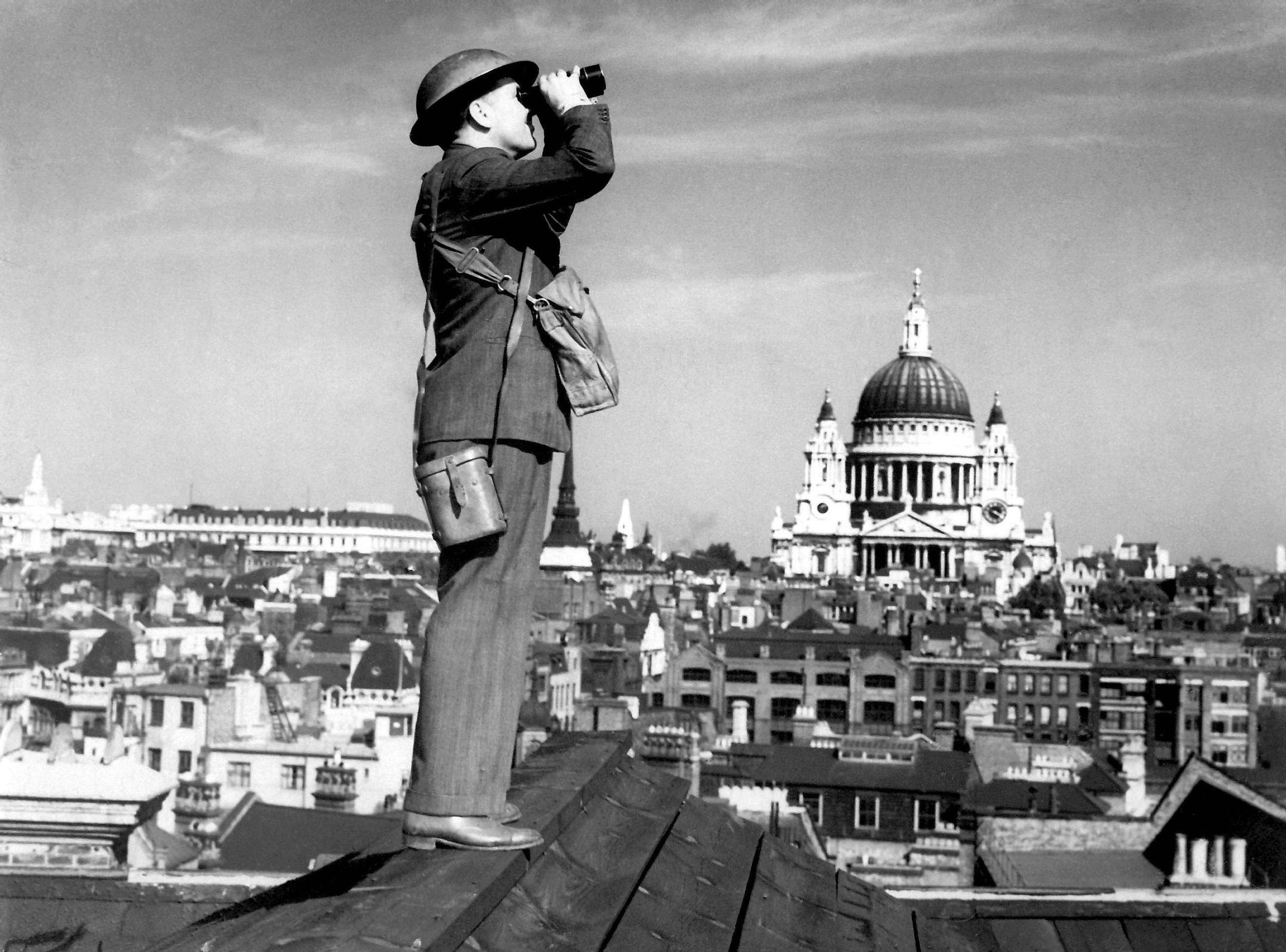 Aircraft spotter searches the sky with binoculars during the Battle of Britain. St. Paul's Cathedral is in the background. World War 2.