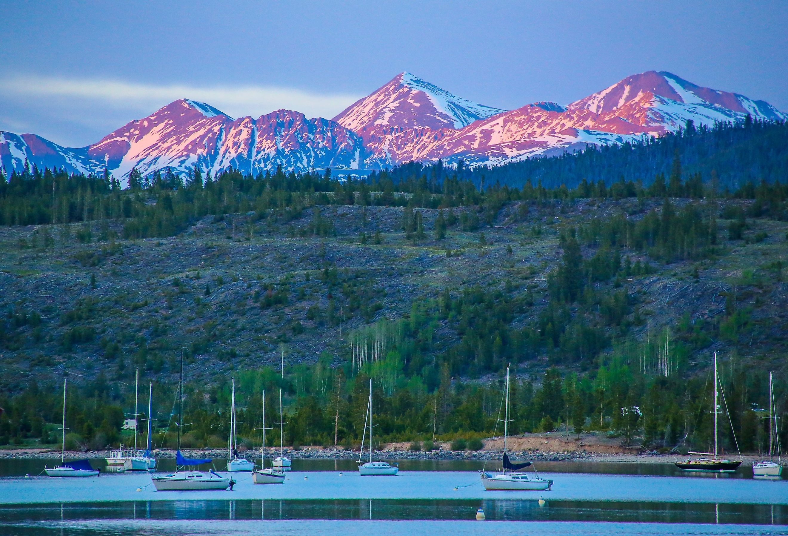 Alpenglow hitting the peaks of Grays and Torreys beyond the Frisco Bay Marina in Frisco, Colorado. Image credit Joey Reuteman via Shutterstock.