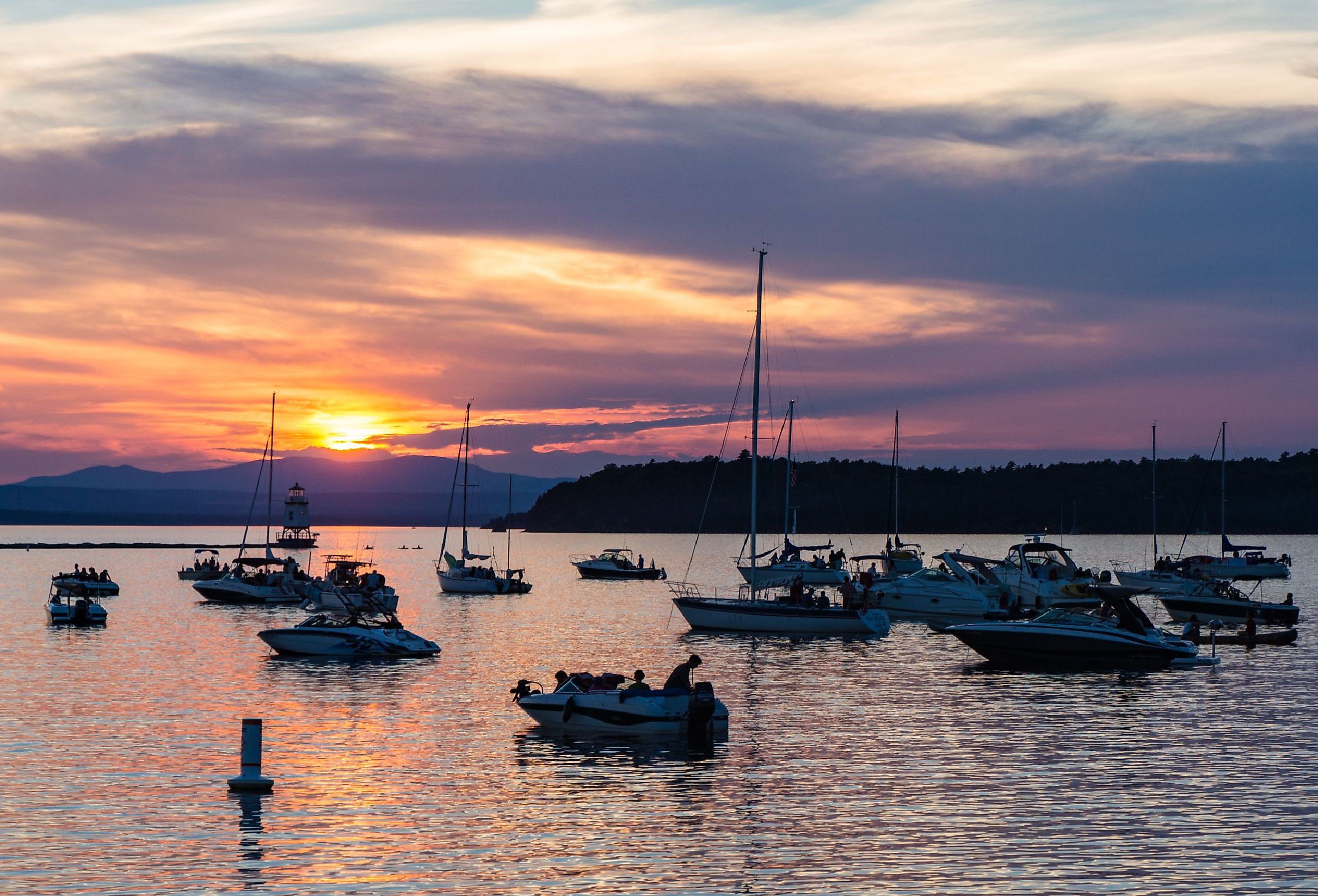 Boaters watching the sunset on Lake Champlain on a summer evening in Vermont. Image credit vermontalm via Shutterstock.