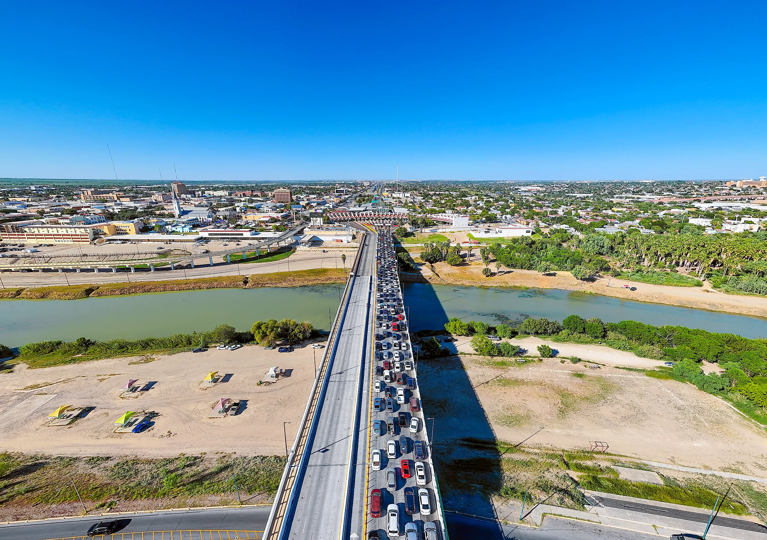 High-angle drone photograph capturing a dense queue of northbound vehicles stretching across the Juarez-Lincoln International Bridge over the Rio Grande. 