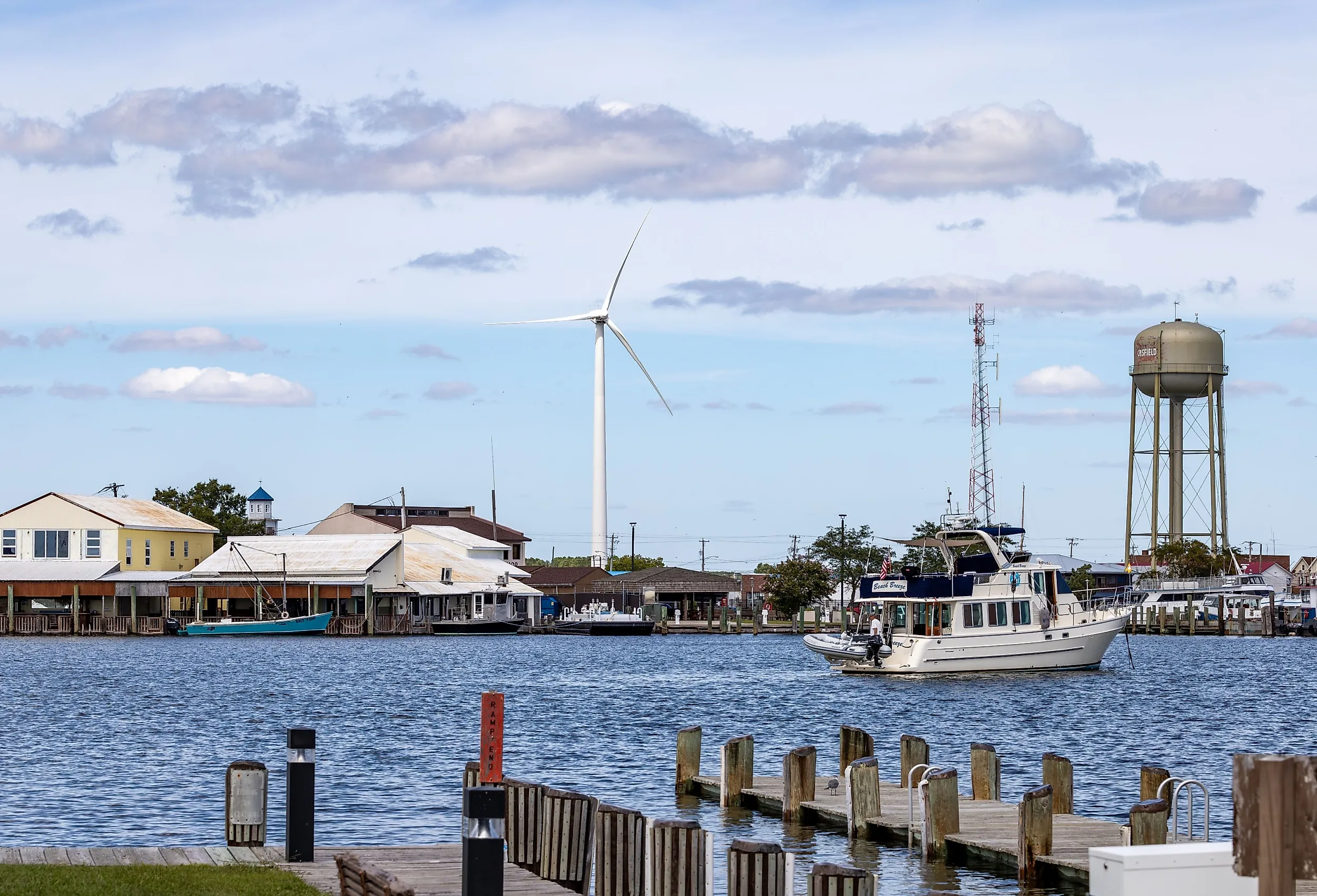 A view of the port in Crisfield with boats, a water tower and a wind turbine. Image credit: Alexanderstock23 via Shutterstock.