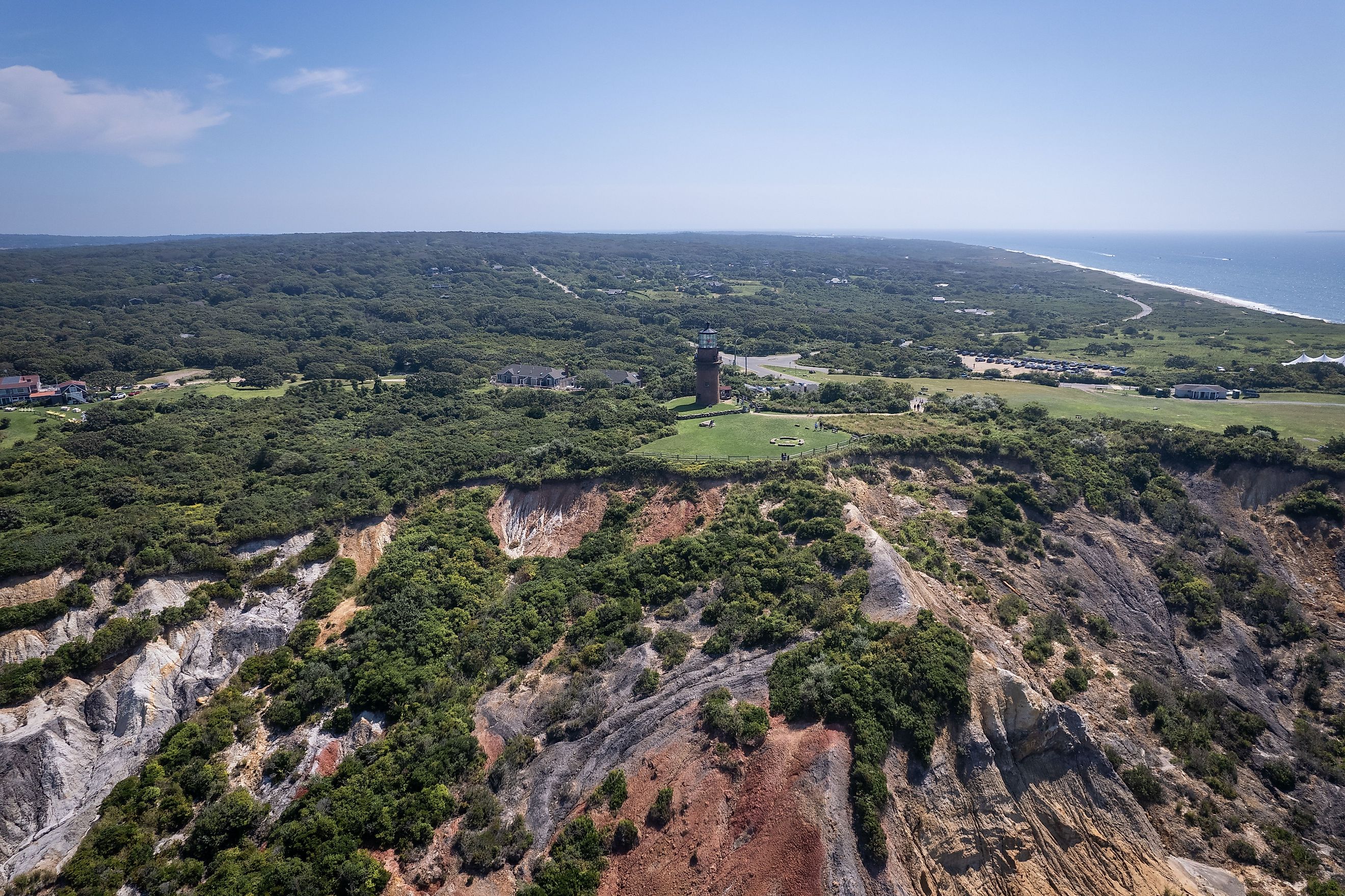 Aerial of scenic cliffs and lighthouse at Gay Head in Martha's Vineyard, with lush greenery and ocean views.
