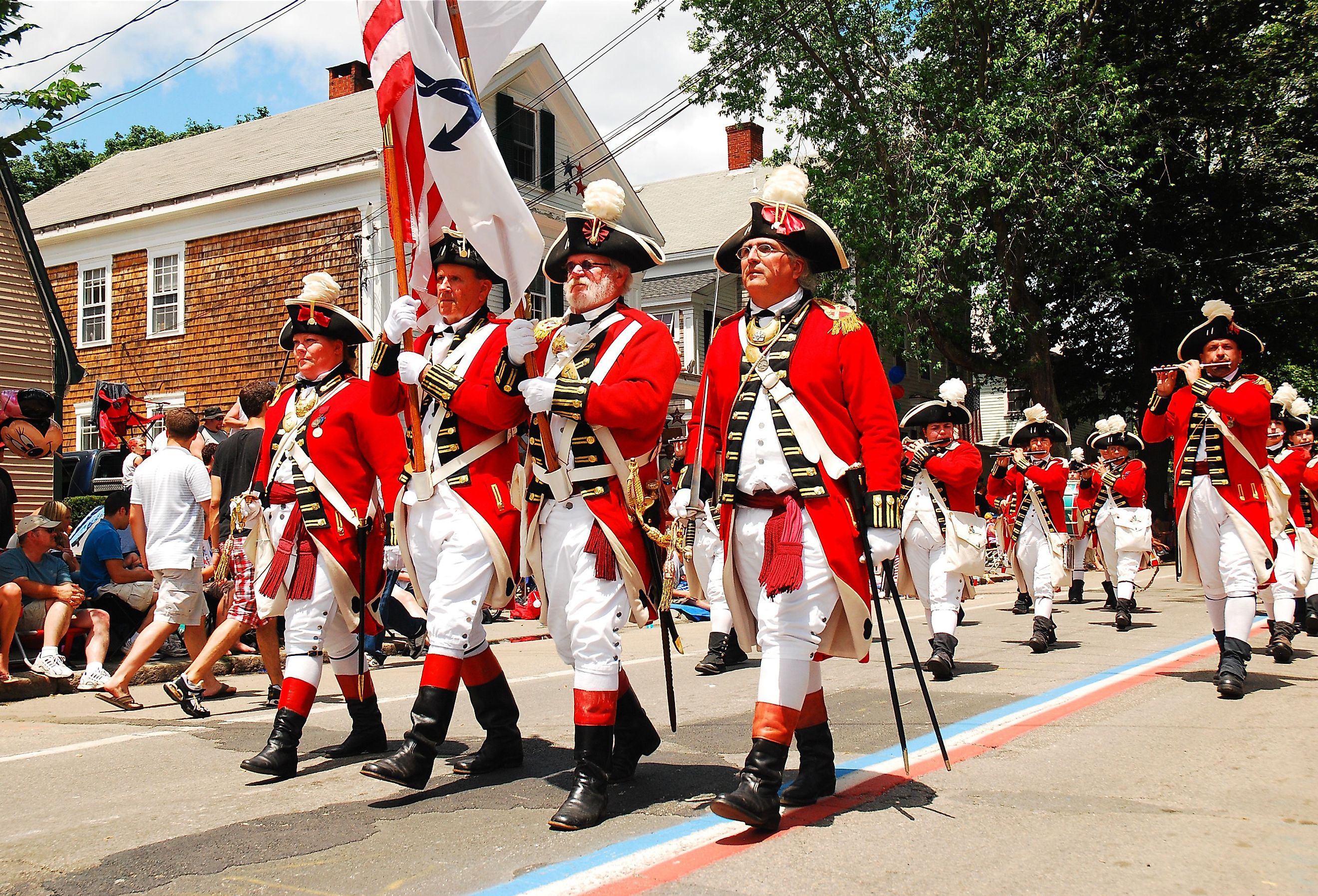 Adults dressed in British red coats from the American Revolution, march in a fourth of July parade in Bristol, Rhode Island. Image credit James Kirkikis via Shutterstock
